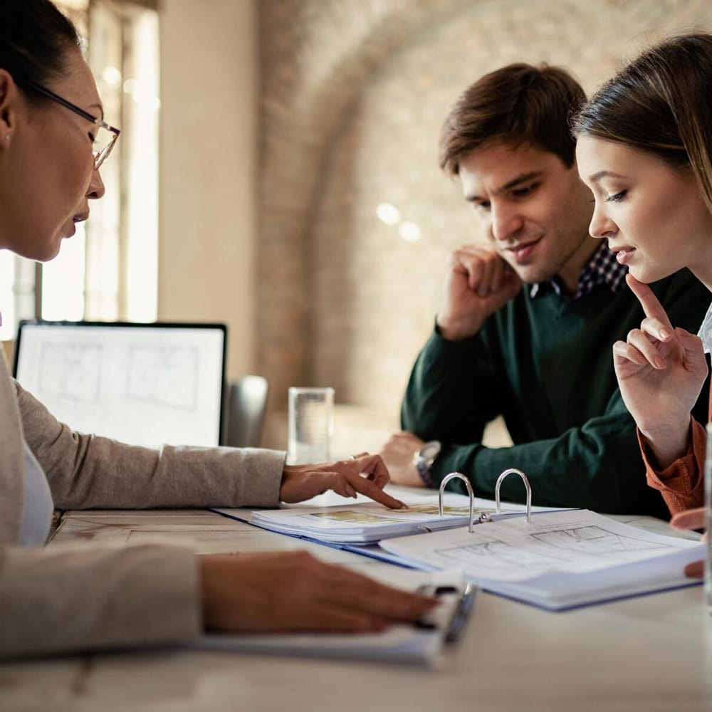 young-man-his-wife-examining-housing-plans-with-real-estate-agent-meeting-office_637285-2810